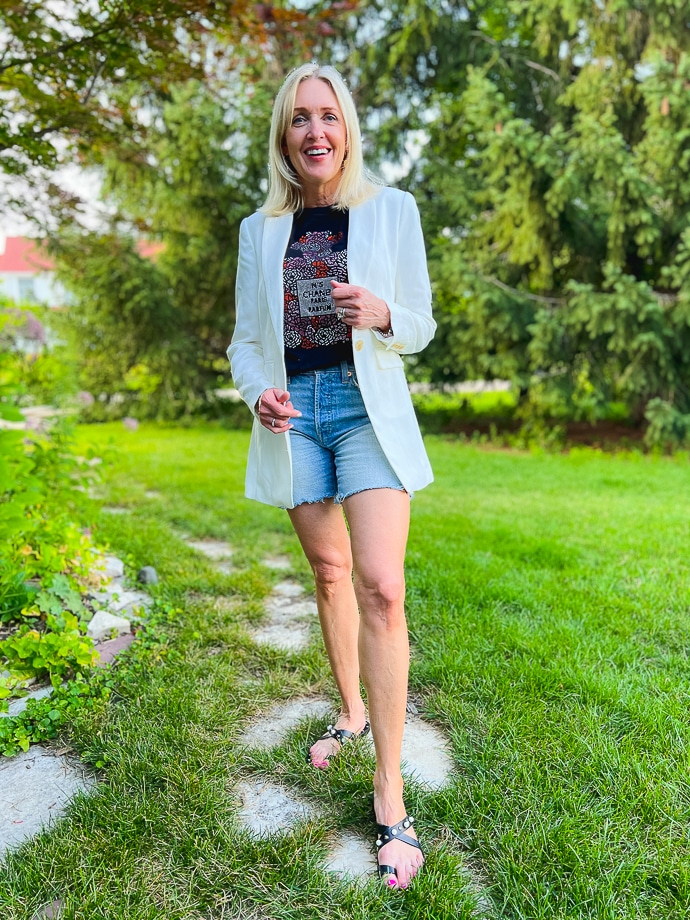 woman wearing denim cut-off shorts, graphic tee and white blazer